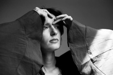 Çağdaş siyah beyaz bir portre. Siyah ceketli. Yüzünün etrafına zarif bir el yerleştirilmiş.