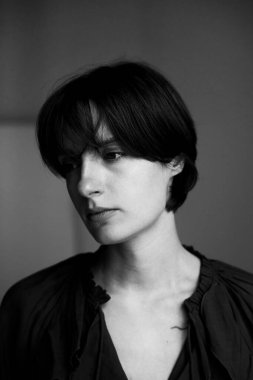 Perili, saç kesimli ve stüdyo ışıklarında yoğun bakışlı genç bir kadının siyah beyaz portresi.