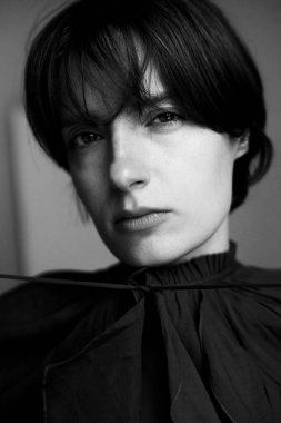 Dramatik chiaroscuro ışıklandırma tekniğinde kısa saçlı genç bir kadının sanatsal siyah beyaz portresi.