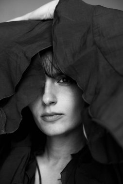 Karamsar siyah beyaz portre dramatik kumaş gölgeleri ve yüksek kontrastlı aydınlatma yüz hatlarını ve dokusunu vurguluyor