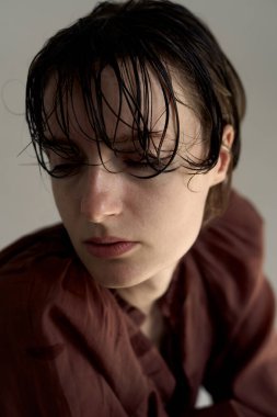 Burgundy kapüşonlu, doğal ışıklandırmalı genç bir kadının ılık renkli portresi yumuşak gölgeler ve rahat bir atmosfer yaratıyor.