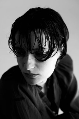 Çağdaş stüdyo fotoğrafçılığı tarzında dağınık saç dokusu ve yüksek kontrastlı aydınlatma içeren dramatik siyah beyaz portre