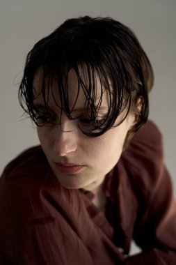 Burgundy kapüşonlu, doğal kıvırcık saçlı ve yumuşak stüdyo ışıklandırmalı genç bir kadının samimi portresi sıcak atmosferik atmosfer yaratıyor.