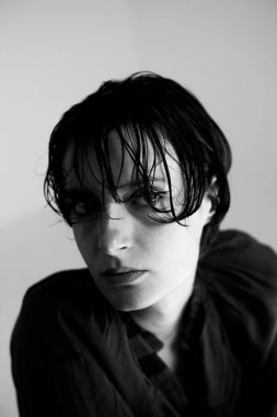 Sanatsal monokrom portresi doğal saç hareketini vurguluyor ve hafif ışıklandırma ve minimalist kompozisyonda derin düşüncelere daldırıyor.