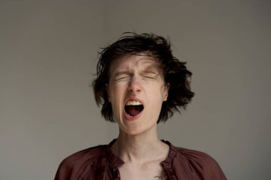 Stüdyoda duygusal olarak bağıran kıvırcık saçlı, etkileyici genç adam.