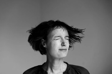 Sakin, dağınık saçlı genç bir kadın. Huzurlu bir anda, yumuşak stüdyo ışıklarıyla yakalandı.