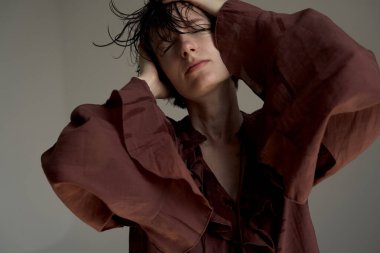 Burgundy süveter giyen genç bir kadın. Elleri başının arkasında. Stüdyoda rahat bir portre çekimi.