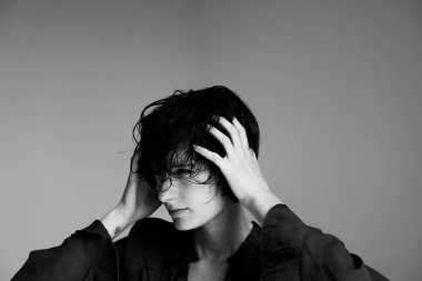 Koyu renk ceketli kadının tek renkli stüdyo portresi duygusal bir anda yüzünü kapatıyordu.