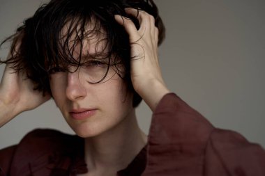 Dalgın saçları olan genç bir adam stüdyo portresi çekilirken el ele tutuşuyor.