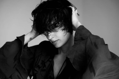 Siyah beyaz, siyah ceketli, alnında stresi gösteren bir genç portresi.