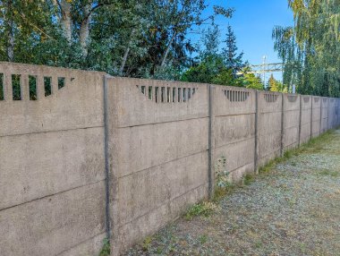 Uzun beton çit panelleri, arka planda ağaçlar olan konutlar arasında sınır oluşturuyor. Yüksek kalite fotoğraf