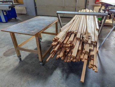 Profesyonel marangoz, endüstriyel atölye deposunda uzun tahta ve kereste malzemeleri organize ediyor. Yüksek kalite fotoğraf