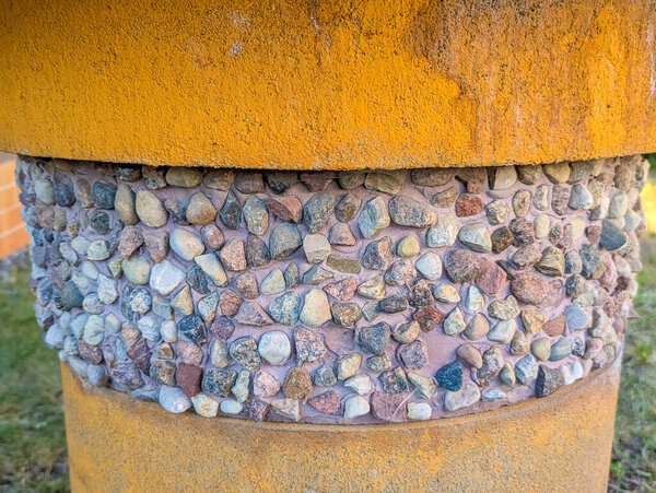 Decorative stone wall with yellow brick top featuring small rounded pebbles creating textured pattern surface. high quality photograph