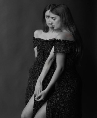 Zarif siyah elbiseli ikiz kardeşler sanatsal monokrom fotoğrafçılık oturumunda nazik pozlarla samimi bir anı paylaşıyorlar. Yüksek kalite fotoğraf