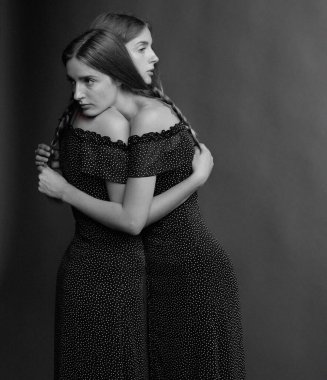 Güzel bir kadın, zarif, siyah, omuzsuz bir elbise içinde. Stüdyo resminde elleri kalçalarında poz veriyor. Yüksek kalite fotoğraf