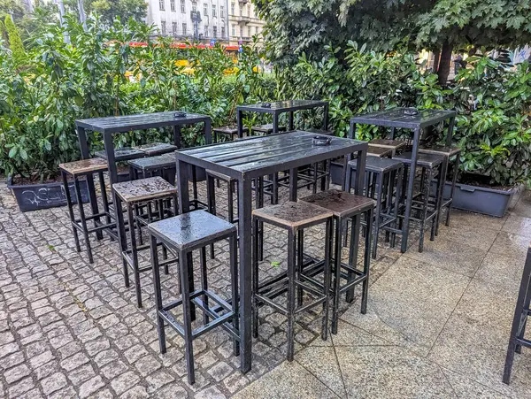 Açık terastaki beyaz yuvarlak masaların etrafına siyah metal sandalyeler yerleştirilmiş restoran verandası mobilyaları düzenleme. Yüksek kalite fotoğraf