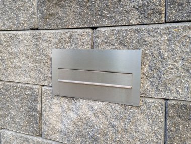 Varşova, Polonya, 20 Eylül 2025. Konut girişinin gri tuğla duvar mimari detaylarına gömülü metal posta kutusu yuvası. Yüksek kalite fotoğraf