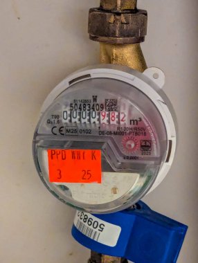 Varşova, Polonya, 20 Eylül 2025. Belirgin kırmızı teftiş etiketine ve nötr iç duvar yüzeyine karşı mavi kapakçık eklentisine sahip ikamet gaz sayacı. Yüksek kalite fotoğraf.