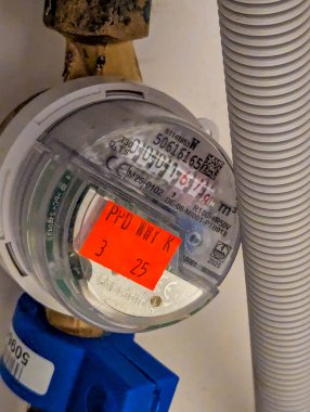 Varşova, Polonya, 20 Eylül 2025. Evdeki gaz ölçme cihazının açılı perspektifi turuncu denetim etiketini gösteriyor mavi valf ve metalik kıvrımlı bağlantı hortumu. Yüksek kalite fotoğraf.