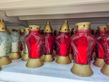 Süslü altın metal tutacaklarda beyaz raflarda sergilenen kırmızı anıt mumları. Yüksek kalite fotoğraf.