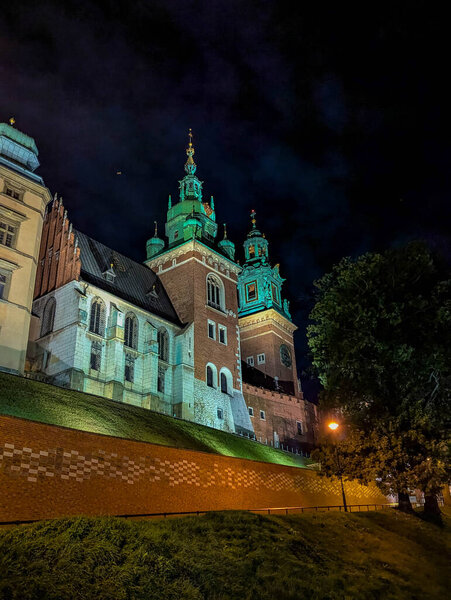 Historic Church of St. Andrew with green copper domes illuminated along cobblestone Grodzka Street during blue hour in old town Krakow, Poland. High quality photograph