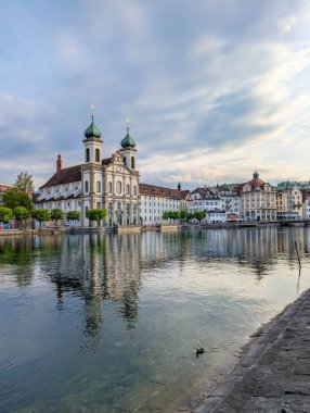 Lucerne, İsviçre, 20 Eylül 2025. İkiz barok kuleleri olan Majestic Cizvit Kilisesi İsviçre 'nin Lucerne kentindeki Reuss Nehri' ne mükemmel bir şekilde yansıyor. Yüksek kalite fotoğraf.