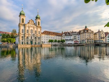 Lucerne, İsviçre, 20 Eylül 2025. Barok Cizvit Kilisesi 'nin panoramik manzarası ve tarihi rıhtım binaları İsviçre' nin Lucerne kentindeki Reuss Nehri 'ne yansıdı. Yüksek kalite fotoğraf.