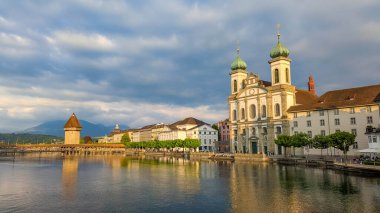 Lucerne, İsviçre, 20 Eylül 2025. Barok Cizvit Kilisesi 'nin ve İsviçre' nin Lucerne kentindeki Reuss Nehri boyunca inşa edilen tarihi binaların üzerinde ılık bir günbatımı parlıyor. Yüksek kalite fotoğraf.
