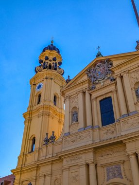 Munich, Germany, May 01, 2025. Theatine Church yellow baroque facade with twin towers and dome against blue sky in Munich Germany Odeonsplatz. High quality photograph