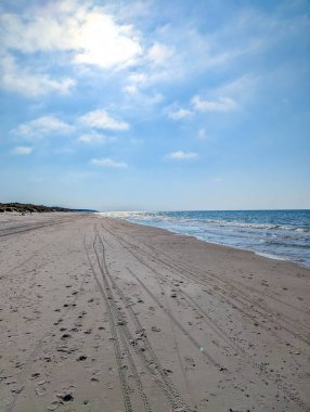 Wide empty sandy beach stretching along Baltic Sea shoreline under cloudy sky near Leba Poland in summer. High quality photograph