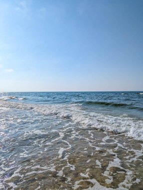Foaming Baltic Sea waves washing sandy beach shore under blue sky near Leba Poland summer coast. High quality photograph