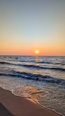 Soft waves washing Baltic Sea shore during magnificent golden sunset near Leba Poland with warm evening light. High quality photograph