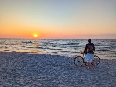 Güneş batarken Baltık Denizi sahilinde bisiklet süren Leba Polonya yakınlarında mavi gökyüzü olan bir kişi. Yüksek kalite fotoğraf