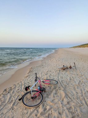 Leba, Polonya, Mayıs 01, 2025. Alacakaranlık vakti Leba Polonya yakınlarındaki boş Baltık Denizi sahilinde martılar ve kıyı manzaralı bisiklet. Yüksek kalite fotoğraf