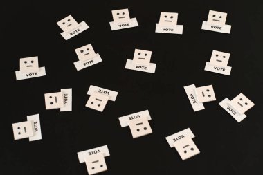 Bir adam bir oy konsepti; İfadesiz yüz ifadesi siyah arka plandaki seçmeni temsil etmek için metin oyuyla emojiyi temsil ediyor