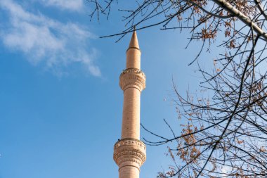 Goreme, Türkiye Camii 'nin minaresi zarif bir şekilde yükseliyor. Kış ağaçlarının narin, çıplak dalları tarafından kıtır mavi gökyüzüne karşı çerçeveleniyor.