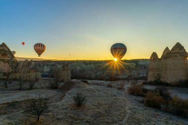 Güneş ışığı, Cappadocia 'da Love Valley' in üzerinde süzülürken sıcak hava balonunun sepetini delip geçer ve nefes kesici bir sahne yaratır..