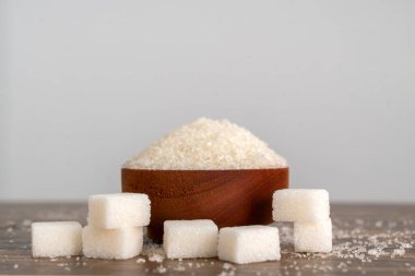 Tahta kasede granüle şekeri ve küp şekeri yan görünüm olarak göster