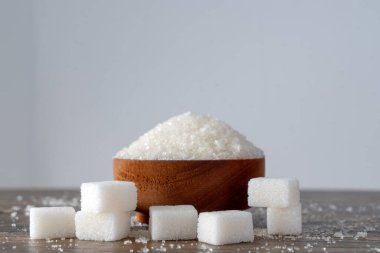 Tahta kasede granüle şekeri ve küp şekeri yan görünüm olarak göster