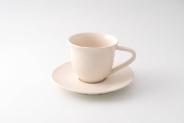Boş bir seramik kahve fincanının beyaz bir arka planda izole edilmiş bir fincan üzerinde durduğu belirsiz bir manzara.
