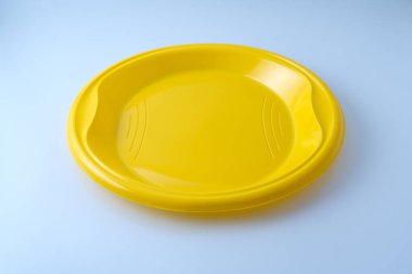 Boş sarı plastik plaka, köşegen 45 derecelik açıyla çekilmiş, beyaz bir arkaplanda izole edilmiş.