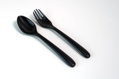 Beyaz arkaplanda Melamine 'den yapılmış siyah kaşık ve çatalın çapraz eğimli görünümü