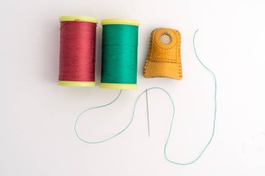 Beyaz arkaplanda yeşil ve kırmızı örtü iplikçikleri ve deri yüksüğün maketlerini sermenin en üst görüntüsü