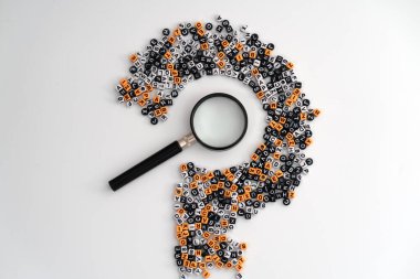 Dağınık harf ve sayıların merkezine yerleştirilmiş bir loupe, merak, analiz ve cevap arayışını sembolize eden büyük bir soru işareti oluşturuyor.