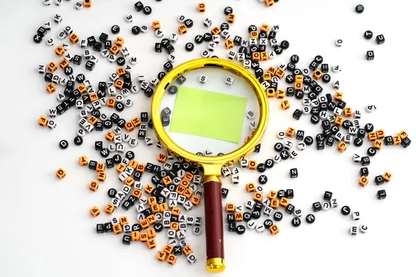 Bir büyüteç altında büyütülmüş boş bir kağıt. Etrafı dağınık harf ve sayılarla çevrili. Keşif potansiyelini, yorumlamayı ve anlamın oluşumunu sembolize ediyor.