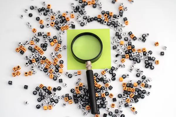 Bir büyüteç altında büyütülmüş boş bir kağıt. Etrafı dağınık harf ve sayılarla çevrili. Keşif potansiyelini, yorumlamayı ve anlamın oluşumunu sembolize ediyor.