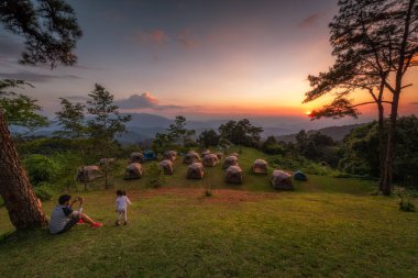 Dad taking pictures of his daughter in sunset viewpoint at Huai Nam Dang National Park, Thailand clipart