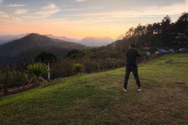 Young Asian men take pictures in the sunset view point of Doi Ang KhangCamping site in Doi Ang Khang ,Chiang Mai Thailand