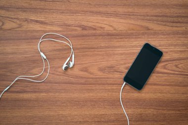 ahşap masa üzerinde kulaklık ile Smartphone