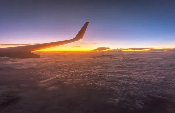 Bir uçak pencereden görüldüğü gibi gökyüzü ve bulutlar. Güzel mavi/mor/turuncu gökyüzü kanadında uçuş sırasında pencere uçak ile seyir.